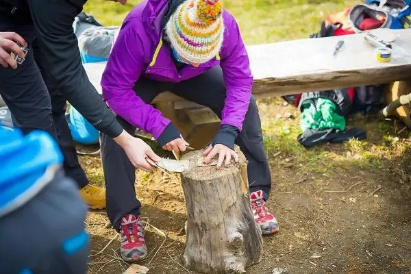 Messer schneidet Holzstück auf einem Baumstumpf während einer Outdoor-Aktivität