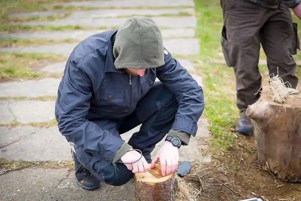 Messer schneidet Zunder auf einem Holzstück während einer Outdoor-Aktivität