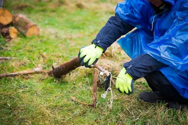 Person befestigt eine Schnur an einem Stock im Gras
