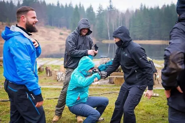 Person hilft anderer Person beim Aufstehen am Wasser