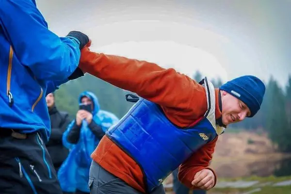 Person in blauer Schwimmweste wird von einer anderen Person festgehalten