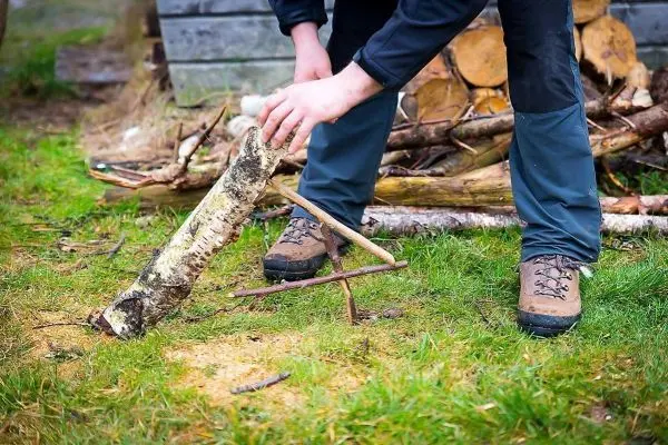 Person richtet Holzstück auf einer Wiese aus