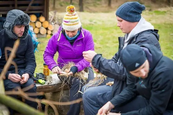 Person sortiert trockenes Gras auf einem Tisch beim Überlebenstraining