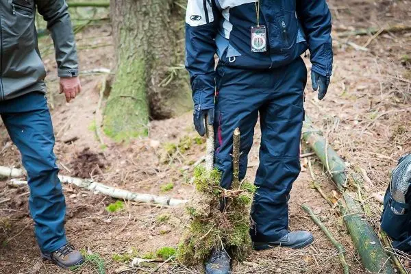 Person steht mit einem Schuh in der Erde im Wald