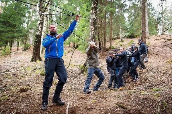 Teilnehmer ziehen an einem Seil während einer Seilquerung im Wald
