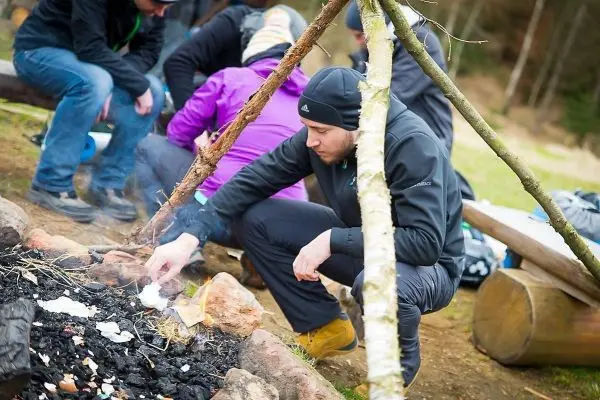 Zunder glimmt in einem kleinen Bodenfeuer neben einer improvisierten Holzstruktur