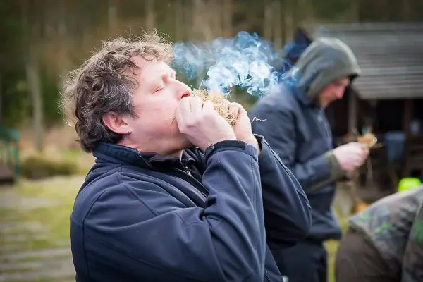 Zunder wird geblasen, während Rauch aufsteigt