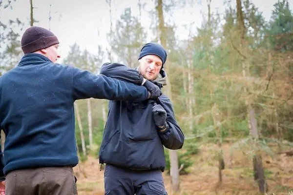Zwei Personen üben eine Selbstverteidigungstechnik im Wald