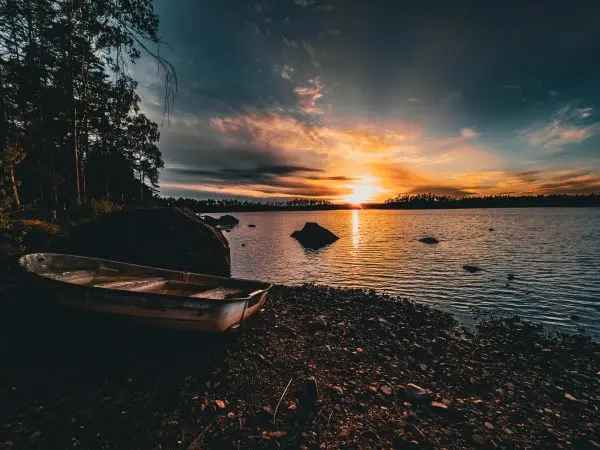 Ein Boot liegt am Ufer eines ruhigen Sees bei Sonnenuntergang