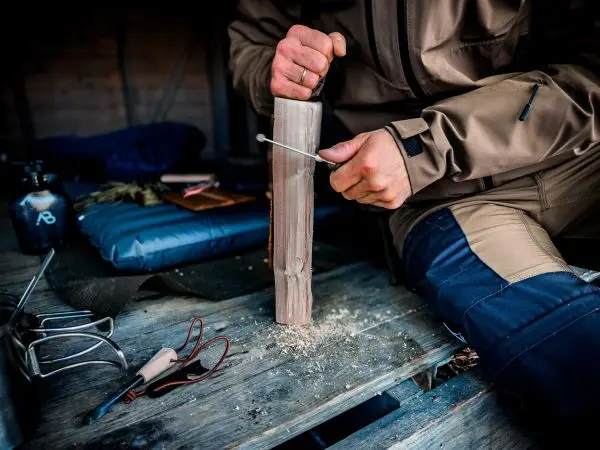 Messer schnitzt eine Kerbe in einen Holzblock auf einem Tisch