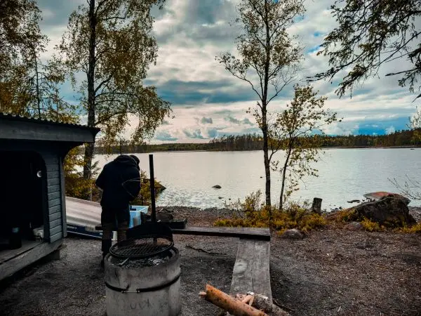 Person bereitet am Grillplatz in der Nähe eines Gewässers eine Mahlzeit vor