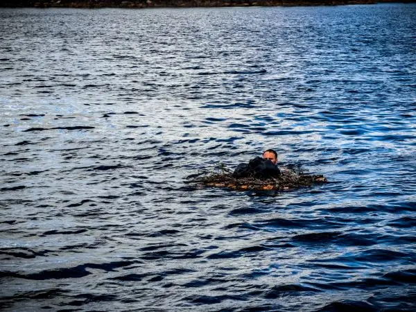 Person schwimmt auf Wasseroberfläche mit dunkler Kleidung