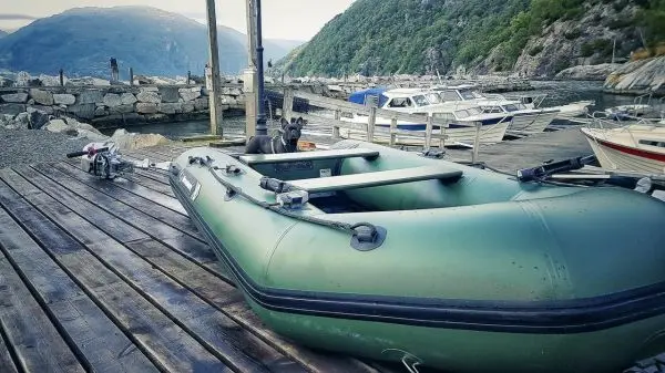 Auf Holzsteg liegendes Schlauchboot mit Außenbordmotor am Hafen