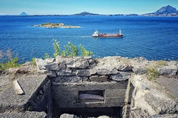 Blick auf das Wasser mit einem Schiff und einer Steinstruktur im Vordergrund
