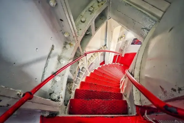 Blick auf eine rote Wendeltreppe mit Handlauf und metallischen Wänden