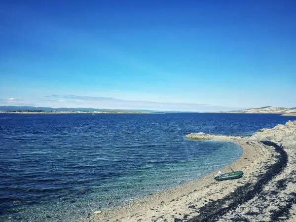 Blick auf ruhiges Wasser mit Sandstrand und Boot am Ufer