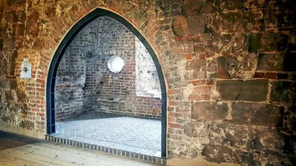 Bogenöffnung in einer Ziegelsteinmauer mit Sicht auf den Innenraum
