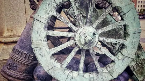 Bronzene Radkonstruktion mit Kanonen und Kugeln im Hintergrund