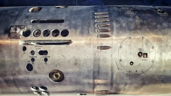 Detailansicht eines metallischen Objekts mit verschiedenen Öffnungen und Beschriftungen