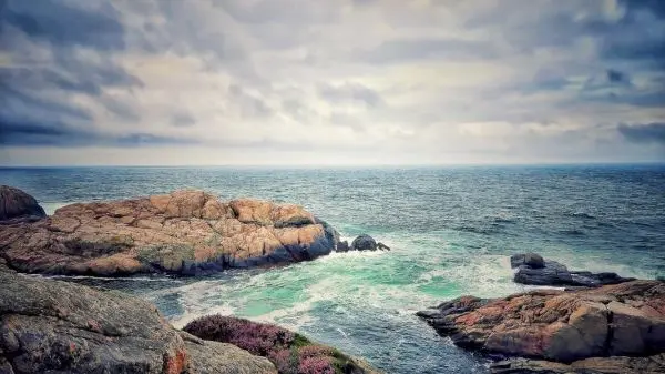 Felsen ragen aus dem Wasser, Wellen brechen sanft an die Küste