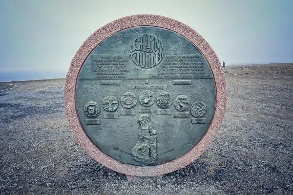 Gedenktafel mit Reliefs und Inschriften auf einem steinigen Untergrund