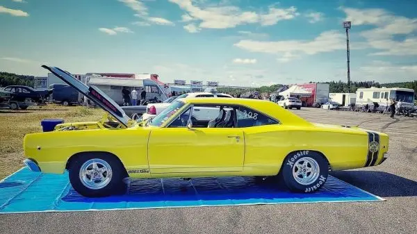 Gelber Muscle-Car mit geöffnetem Motorhaube auf einer blauen Plane