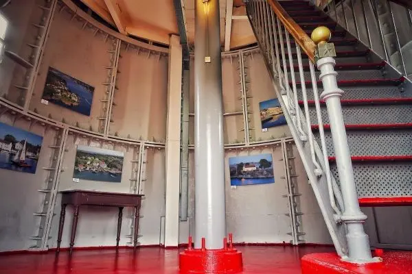 Innenansicht eines Leuchtturms mit Treppe und Bildern an der Wand