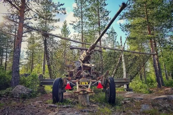 Kanone steht auf einem Holzgestell im Wald