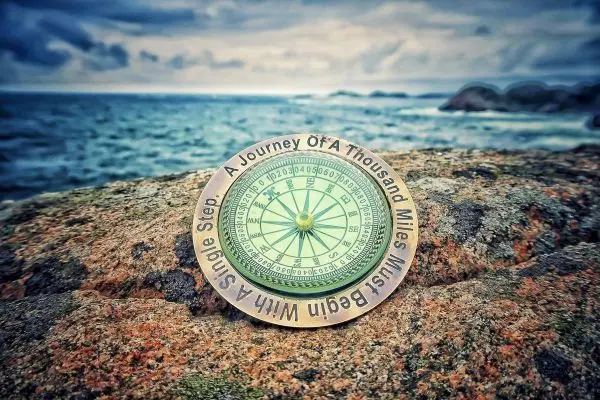 Kompass liegt auf einem Felsen mit Blick auf das Meer