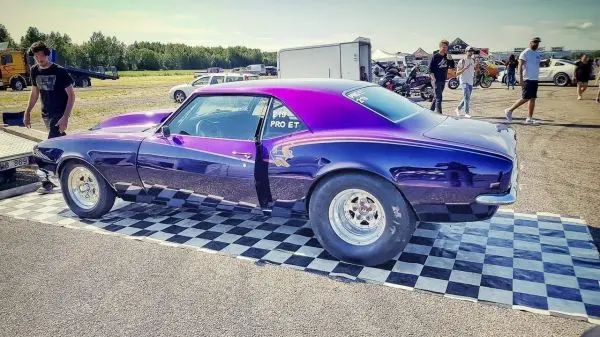 Lila Rennwagen steht auf einem schwarz-weißen Schachbrettmuster