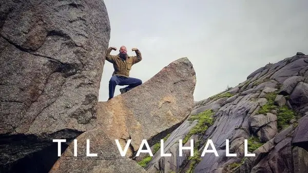 Mann posiert auf einem großen Felsen in einer felsigen Landschaft