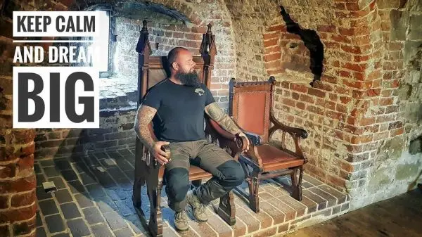 Mann sitzt auf einem Holzstuhl in einem gemauerten Raum