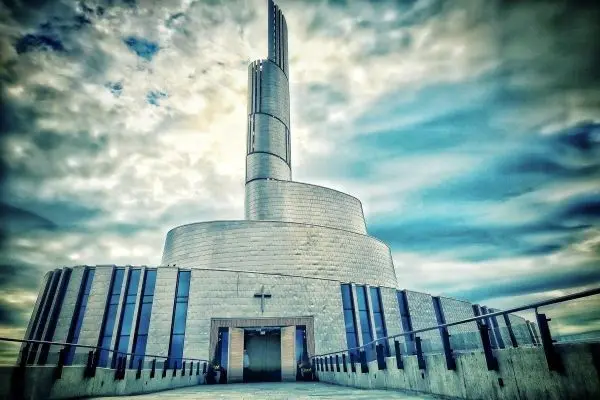 Moderne Architektur mit geschwungener Fassade und hohem Turm unter bewölktem Himmel