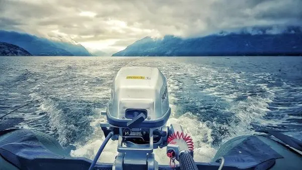 Motorboot fährt über ruhiges Wasser mit Wellenbildung im Hintergrund