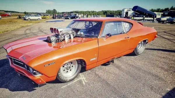 Oranger Rennwagen mit aufgeladenem Motor und breiten Reifen auf einer Rennstrecke