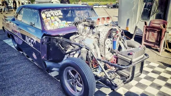 Renntuning-Auto mit offenem Motorraum und sichtbarem Turbolader auf einer Rennstrecke