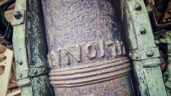 Rostige Metalloberfläche mit eingravierter Beschriftung und sichtbaren Schrauben