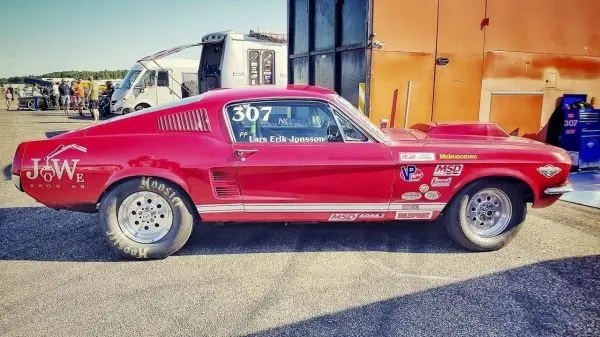 Rotes Rennfahrzeug mit breiten Reifen steht auf asphaltierter Fläche