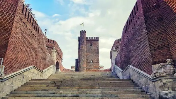 Treppenaufgang zu einer Backsteinburg mit einem Turm und Fahne oben