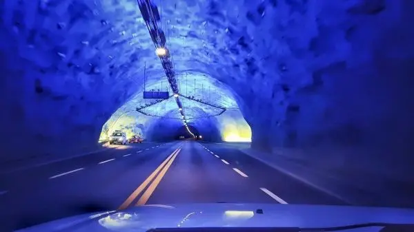 Tunnel mit blauer Beleuchtung und Fahrbahnmarkierungen, Fahrzeug fährt hindurch