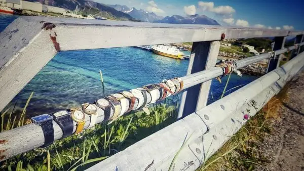 Uhren sind an einem Geländer entlang einer Küstenstraße befestigt