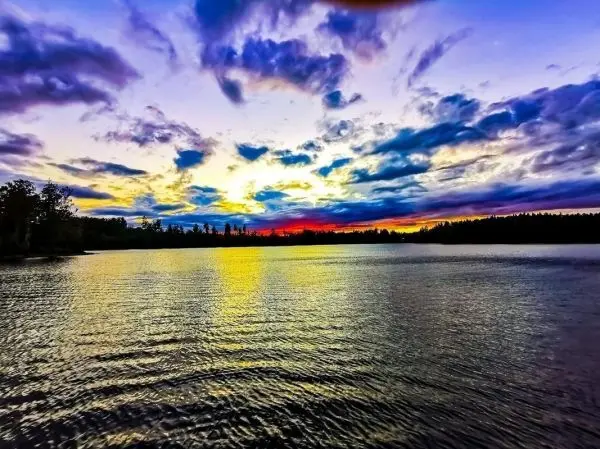 Blick auf einen See mit reflektierenden Wellen und buntem Sonnenuntergangshimmel