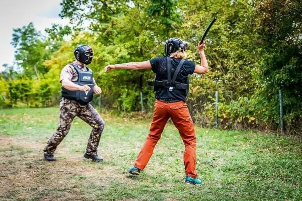 Kämpfer mit Schutzkleidung führt Schlag mit Stock gegen einen anderen Kämpfer aus