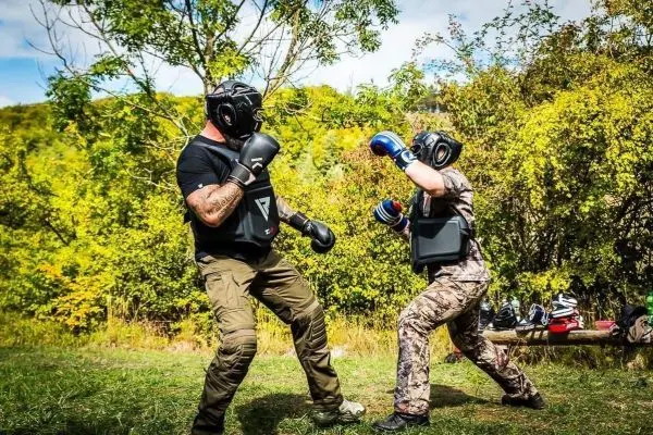 Zwei Kämpfer im Schutzanzug führen ein Training im Freien durch