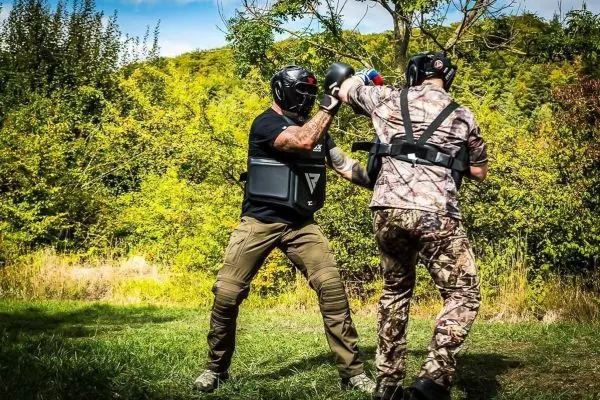 Zwei Personen in Schutzausrüstung führen einen Trainingskampf im Freien durch