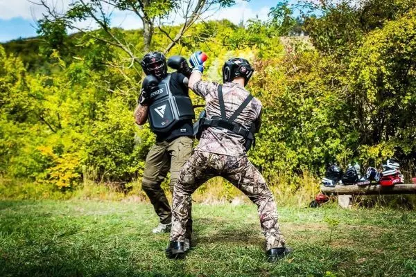 Zwei Personen in Schutzausrüstung üben Boxtechniken im Freien