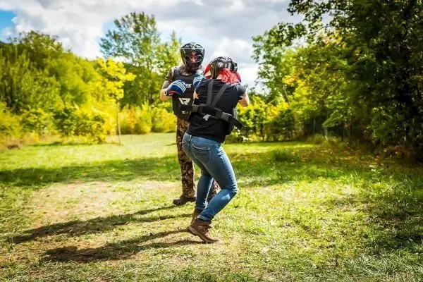 Zwei Personen in Schutzausrüstung üben eine Kampfsituation im Freien
