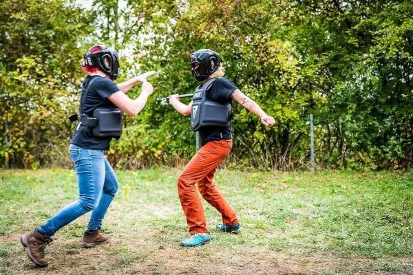 Zwei Personen in Schutzausrüstung üben eine Kampfsituation im Freien