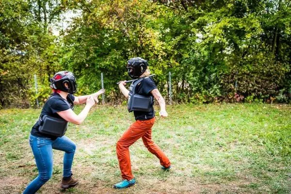 Zwei Personen in Schutzausrüstung üben einen Kampf im Freien