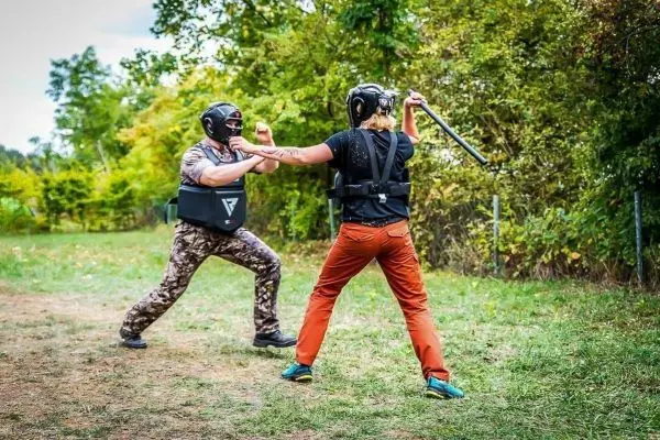 Zwei Personen in Schutzausrüstung üben einen Kampf mit einem Stock